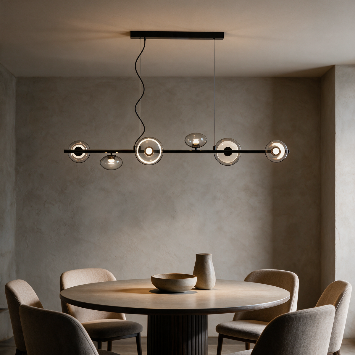 Meridian Linear Chandelier in Black and Smoke Gray above a round dining table in warm evening light