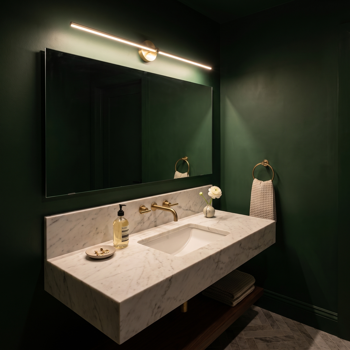 Arlen Gold linear LED wall light above a vanity mirror in a marble powder room