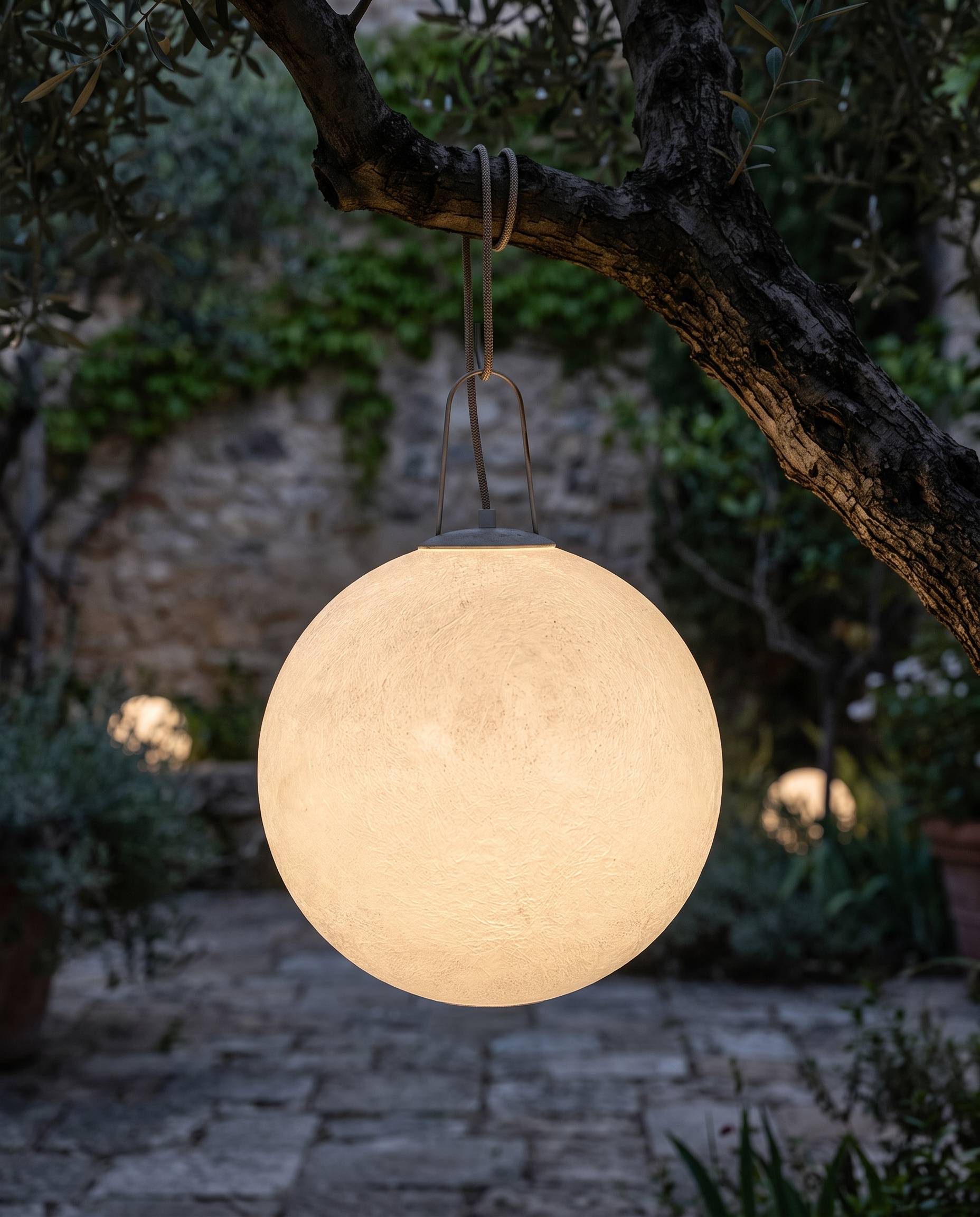 Outdoor moon lamp hanging from a tree in a courtyard at night