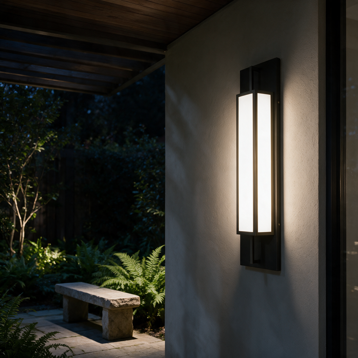 Linnea wall light in a covered walkway beside a garden courtyard at night