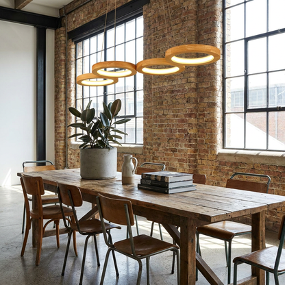 Sylva four ring wood LED pendant light above a communal table in an open-plan loft