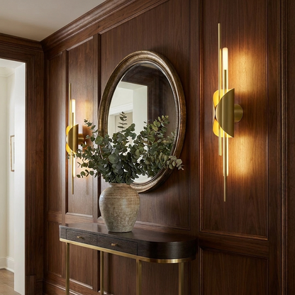 Verlaine natural brass linear wall sconce on a panelled entryway wall above a console table