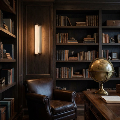 Modern marble sconce casting warm light in a dark oak study with leather chair