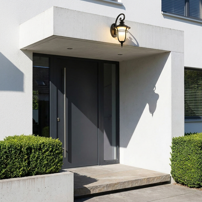 Black outdoor lantern sconce on modern white entry canopy above charcoal pivot door