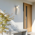 White cement minimalist outdoor wall light on render facade beside oak front door