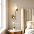 Butterfly wing wall sconce lit beside a tufted headboard in a serene primary bedroom