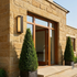 Linear outdoor wall light on a sandstone clad house facade beside a glazed front door in daylight