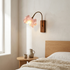 Cherry blossom wall sconce lit beside a low oak headboard in a calm bedroom