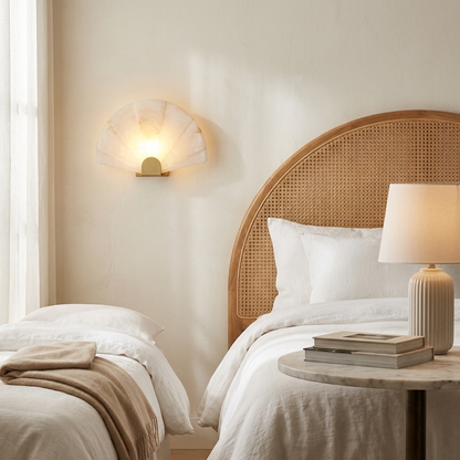 Beaune Scalloped Marble Wall Sconce in a bedroom beside a cane headboard