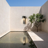 Black geometric stone wall light on plaster courtyard wall with reflecting pool