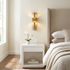 Dorothea Textured Resin Wall Sconce gold in a bedroom beside a wingback headboard