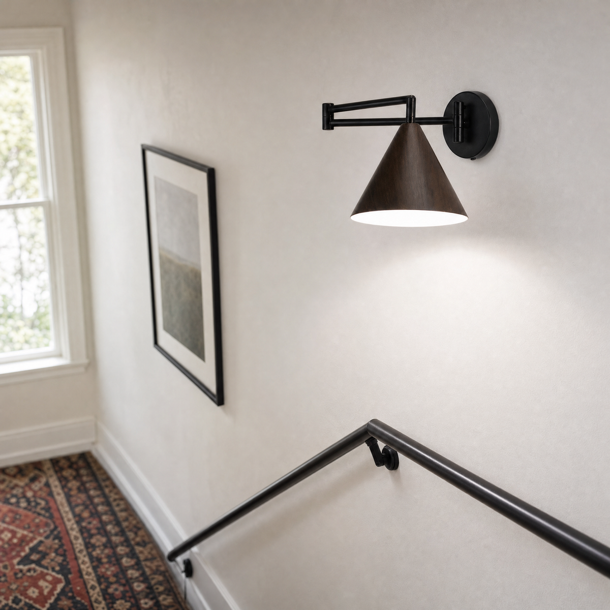 Soren Nordic Swing Arm Wall Sconce in Walnut with white light on a stairwell landing wall