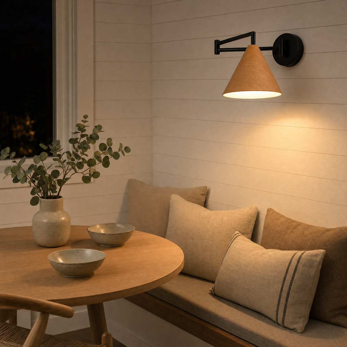 Soren Nordic Swing Arm Wall Sconce in Wood with warm light above a Scandinavian dining nook bench
