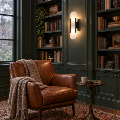 Alba Alabaster Wall Sconce in Black beside green bookshelves in a home library reading nook