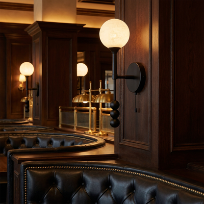 Isaure matte black wall sconce on the wall of an upscale American steakhouse dining room with leather booths