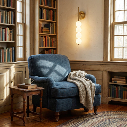 Berenice gold wall sconce beside a reading chair in a cozy home library of a Cape Cod house